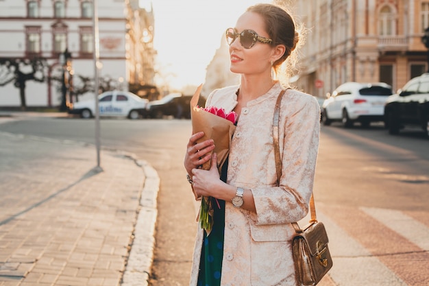 Joven y bella mujer elegante caminando por las calles de la ciudad en la puesta del sol