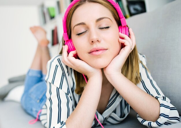 Joven y bella mujer escuchando música en casa.