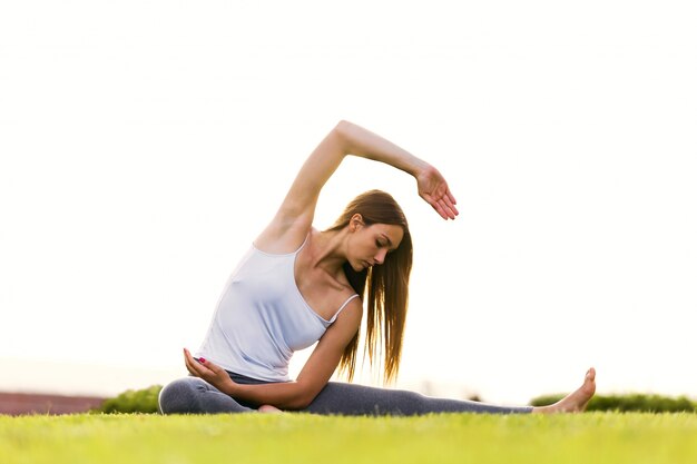 Joven y bella mujer haciendo yoga en la calle.