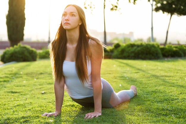 Joven y bella mujer haciendo yoga en la calle.