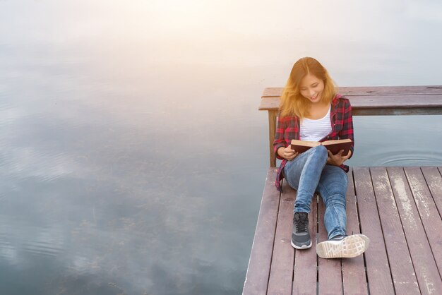 joven y bella mujer inconformista relajante sentado en el muelle de lectura b