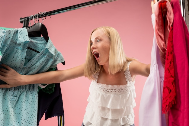 Foto gratuita la joven y bella mujer mirando vestidos y probándose mientras elige en la tienda