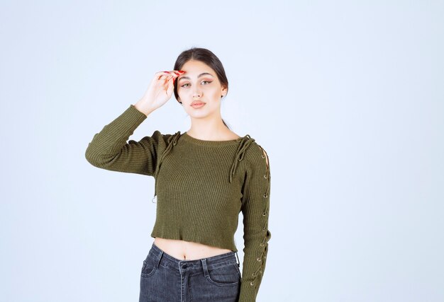 Una joven y bella mujer modelo de pie y tocando la frente.