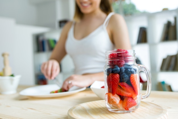 Joven y bella mujer preparando el desayuno en casa.