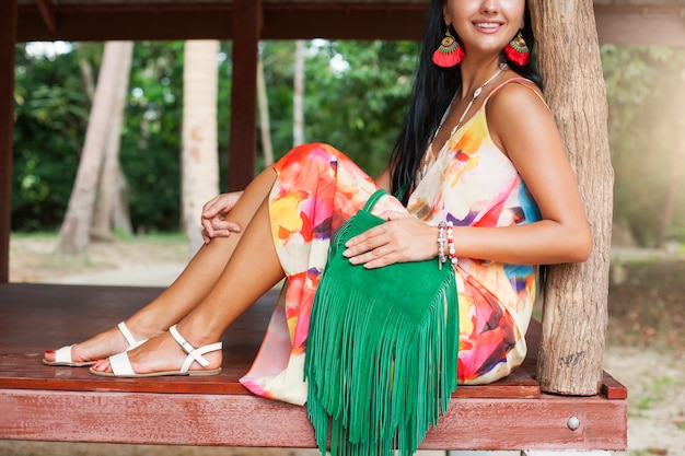 Foto gratuita joven y bella mujer sexy en vestido colorido, estilo hippie de verano, vacaciones tropicales, bolso verde con flecos, accesorios, manos de cerca con pulseras, dedos, manicura