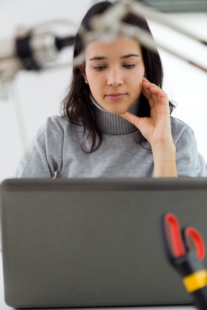 Joven y bella mujer usando su computadora portátil en casa.