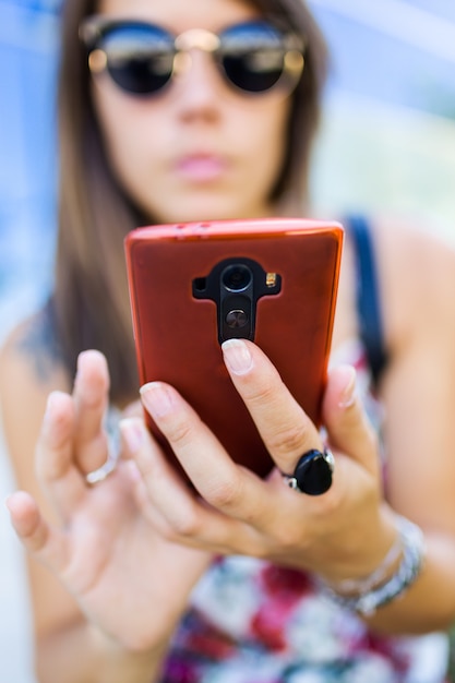 Joven y bella mujer utilizando su teléfono móvil en la calle.