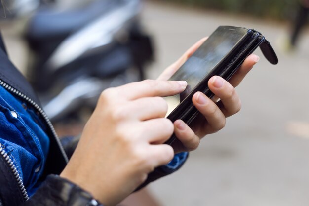 Joven y bella mujer utilizando su teléfono móvil en la calle.