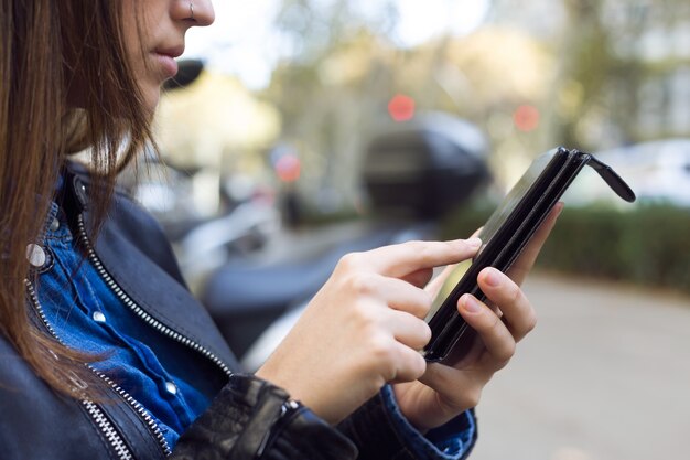 Joven y bella mujer utilizando su teléfono móvil en la calle.