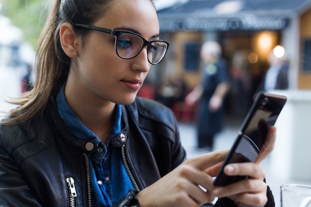 Joven y bella mujer utilizando su teléfono móvil en la calle.