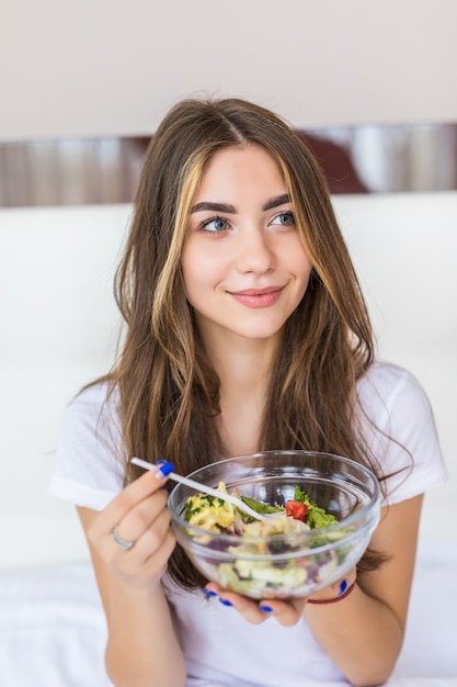 Foto gratuita joven y bella mujer vegetariana comiendo ensalada verde fresca en casa