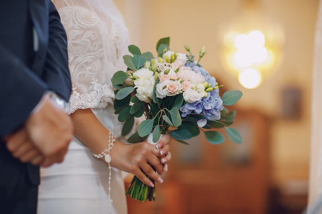 Una joven y bella novia está de pie con su marido en una iglesia