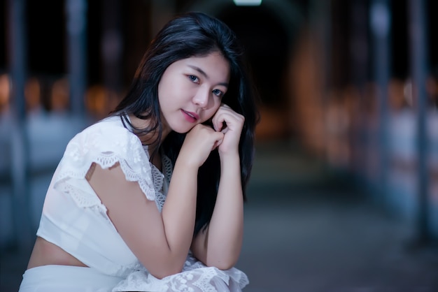 Joven belleza mujer en vestido blanco de luz de noche