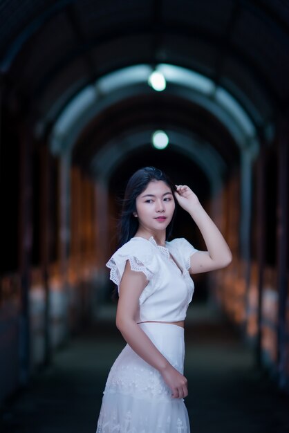 Joven belleza mujer en vestido blanco de luz de noche