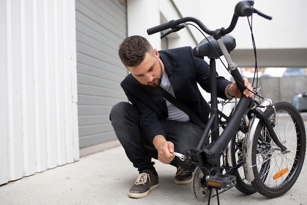 Joven con una bicicleta plegable en la ciudad