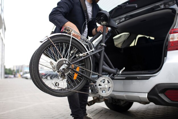 Joven con una bicicleta plegable en la ciudad