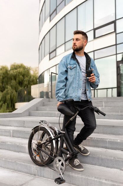 Joven con una bicicleta plegable en la ciudad