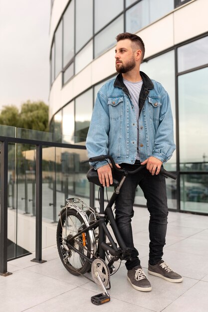 Joven con una bicicleta plegable en la ciudad