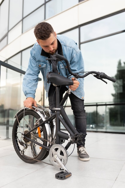 Joven con una bicicleta plegable en la ciudad