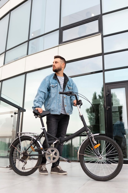 Joven con una bicicleta plegable en la ciudad