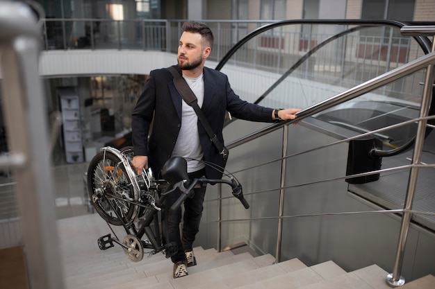 Joven con bicicleta plegable en escalera mecánica