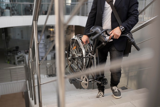 Joven con bicicleta plegable en escalera mecánica