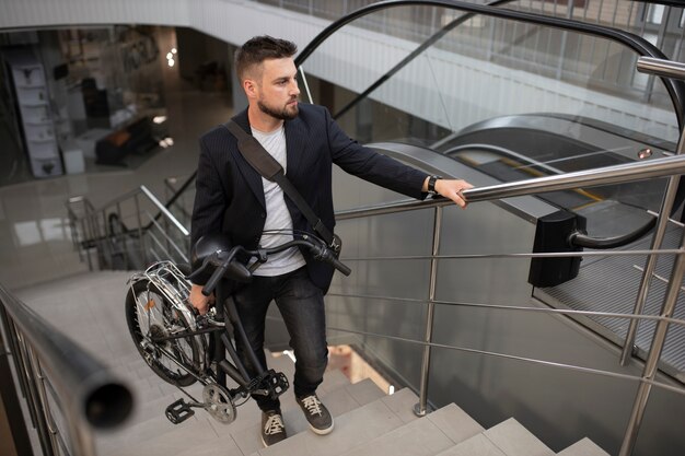 Joven con bicicleta plegable en escalera mecánica