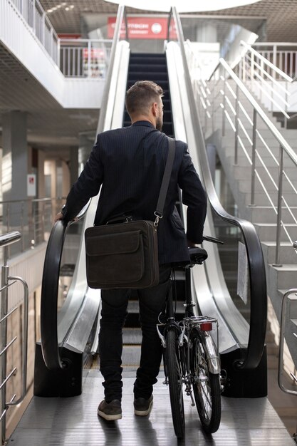 Joven con bicicleta plegable en escalera mecánica