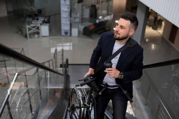 Joven con bicicleta plegable en escalera mecánica