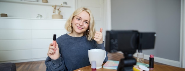 Foto gratuita una joven blogger de belleza carismática, una adolescente, graba un video de sí misma aplicando máscara y revisando el maquillaje.