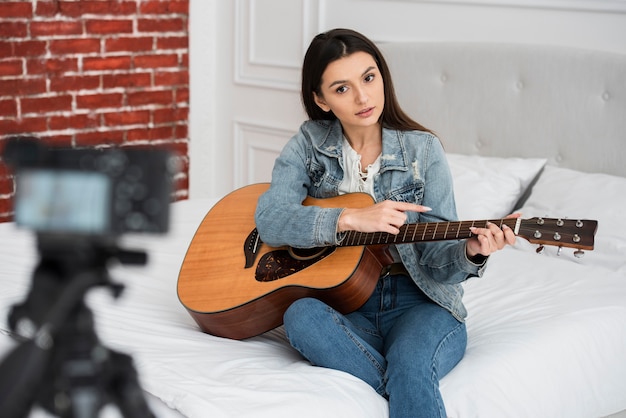 Joven blogger enseñando a tocar la guitarra