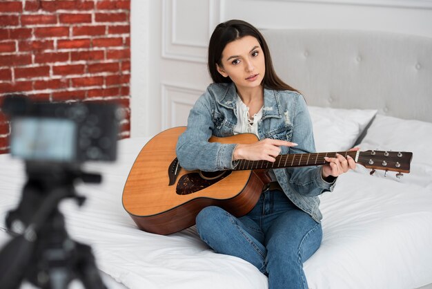 Joven blogger enseñando a tocar la guitarra