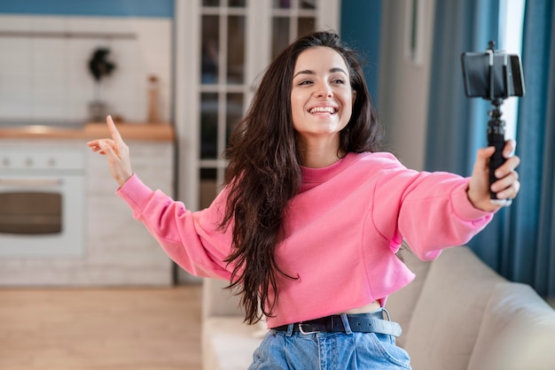 Joven blogger feliz usando selfie stick y hablando por teléfono