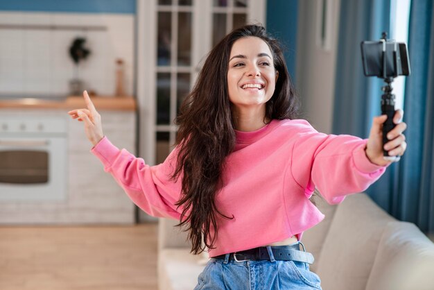 Joven blogger feliz usando selfie stick y hablando por teléfono