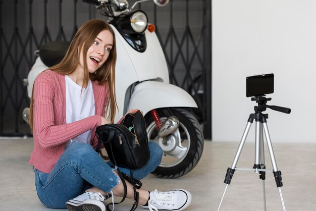 Joven blogger se graba sentada junto a su moto con su bolso