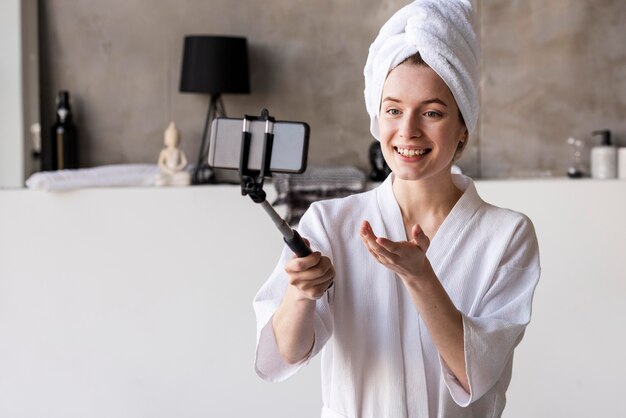 Joven blogger grabando en bata de baño