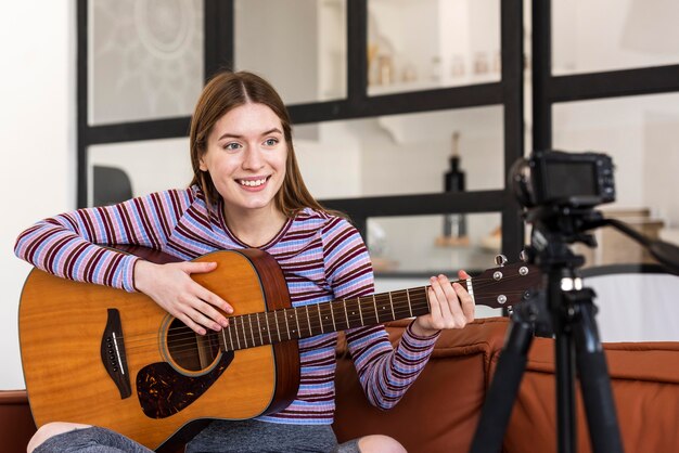 Joven blogger grabando a sí misma sosteniendo la guitarra