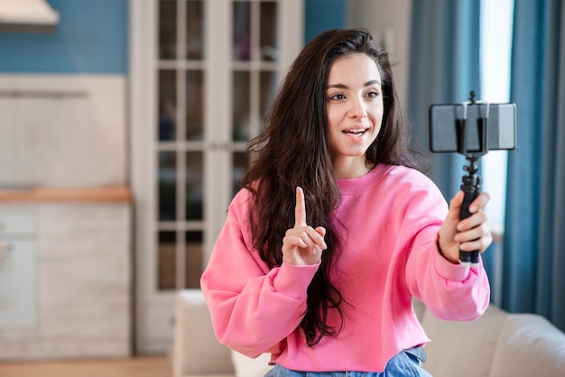 Joven blogger usando selfie stick y hablando por teléfono