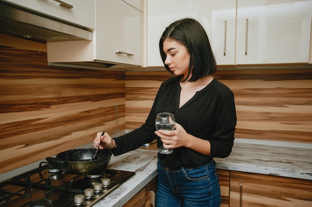 joven y bonita morena de pie en la cocina