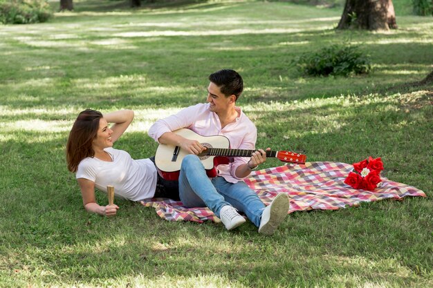 Joven bonita pareja haciendo un picnic en el parque