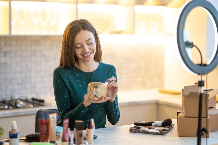 Foto gratuito una joven bonita con un vestido verde mostrando consejos de maquillaje