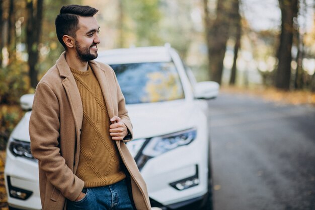 Joven en el bosque con abrigo en el coche