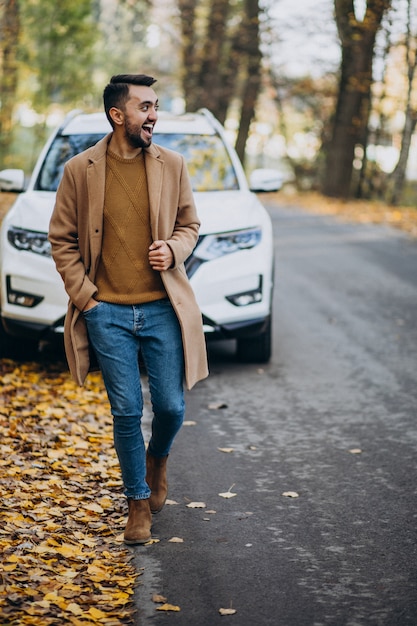 Joven en el bosque con abrigo en el coche