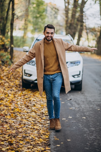 Joven en el bosque con abrigo en el coche