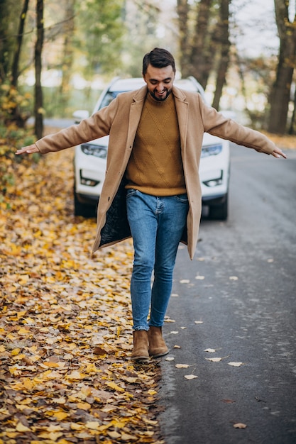 Joven en el bosque con abrigo en el coche