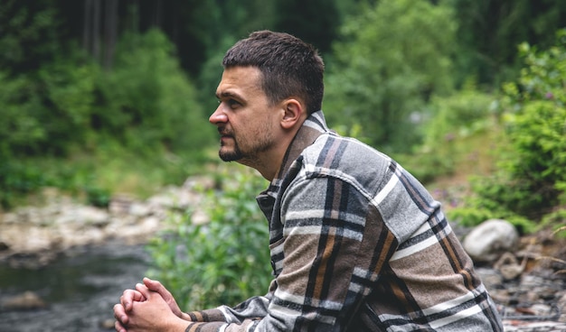 Foto gratuita un joven en el bosque cerca del río disfruta de la naturaleza un alto