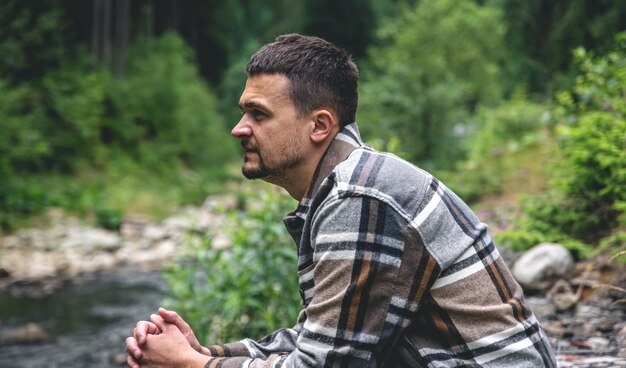 Un joven en el bosque cerca del río disfruta de la naturaleza un alto