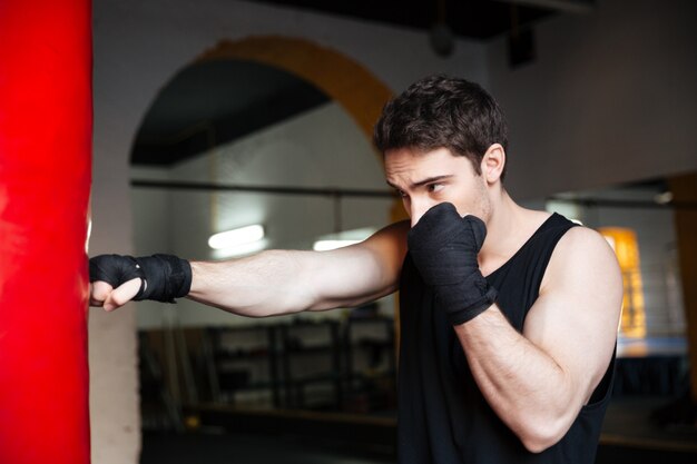 Joven boxeador entrenando con saco de boxeo