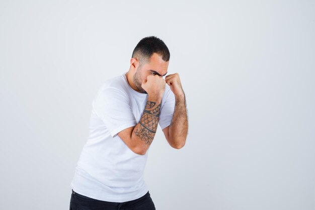 Joven boxeando en camiseta blanca y luciendo poderoso