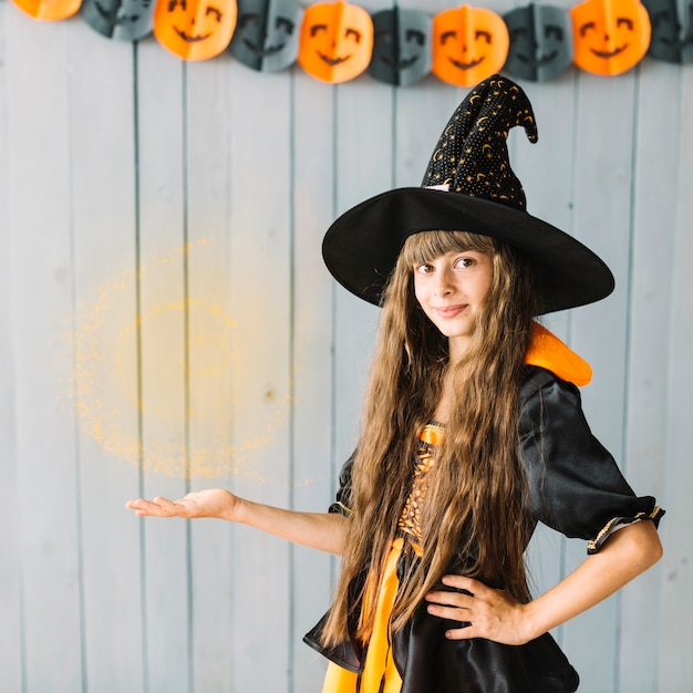 Joven bruja mostrando brujería en Halloween